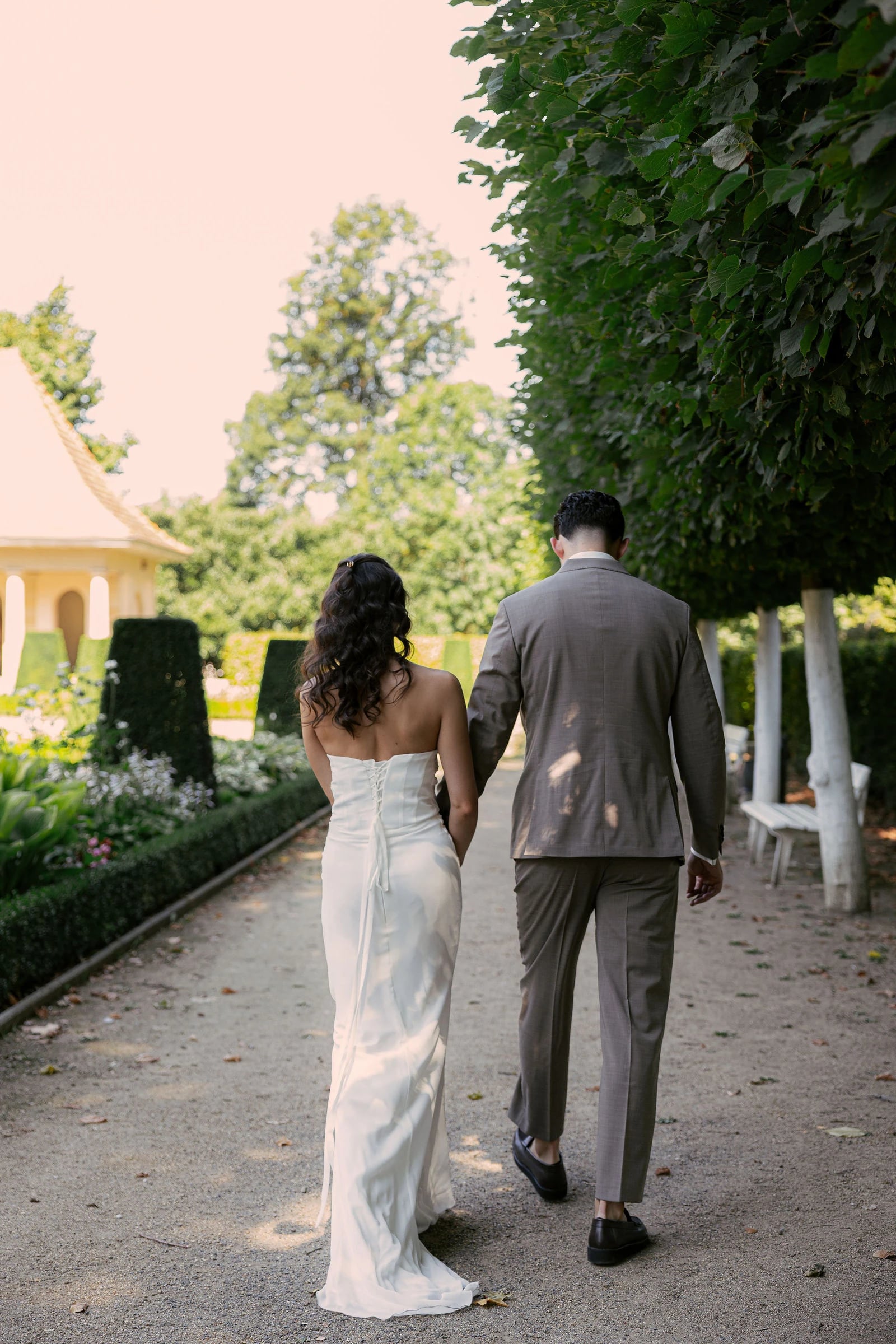 Ein Brautpaar geht Hand in Hand durch den Schlossgarten